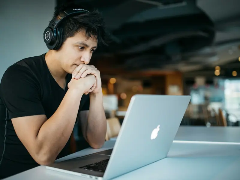 Homem com fones de ouvido estudando em frente a um notebook